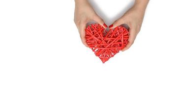 two female hands hold a red wicker heart on a white background, the concept of gratitude, kindness photo