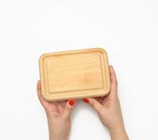 female hand with red manicure holds empty wooden rectangular kitchen chopping board on white background photo