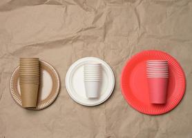 stack of paper cups and round plates on a brown paper background photo