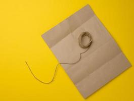 blank brown kraft paper bag and jute rope on yellow background photo