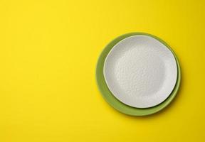 empty round white plate for main courses on a yellow background, top view photo