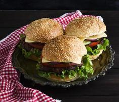 three burgers with a meat chop, vegetables and cheese photo
