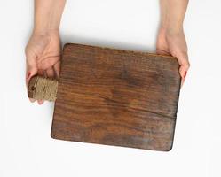 female hands hold empty rectangular brown wooden chopping board isolated on white background photo