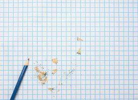 sharpened wooden pencil with shavings on a checkered paper sheet photo