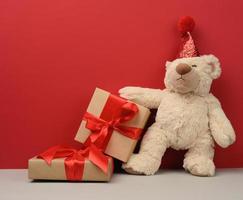 teddy bear in a red festive hat holds a pink sheet of paper photo