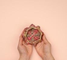 dos manos femeninas sosteniendo un nido decorativo en miniatura de madera de mimbre foto