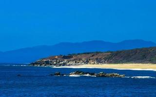 Beautiful rocks cliffs view waves at beach Puerto Escondido Mexico. photo