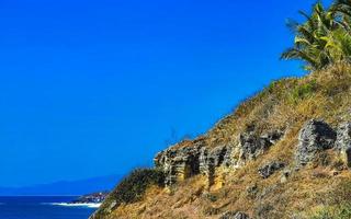 Beautiful rocks cliffs view waves at beach Puerto Escondido Mexico. photo