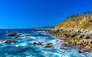 Beautiful rocks cliffs view waves at beach Puerto Escondido Mexico. photo