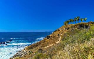 Beautiful rocks cliffs view waves at beach Puerto Escondido Mexico. photo