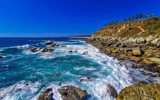 Beautiful rocks cliffs view waves at beach Puerto Escondido Mexico. photo