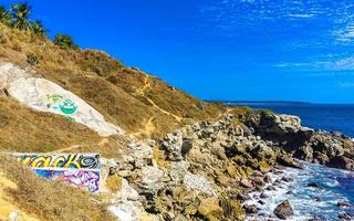 Beautiful rocks cliffs view waves at beach Puerto Escondido Mexico. photo