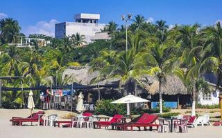 Palms parasols sun loungers beach waves Puerto Escondido Mexico. photo