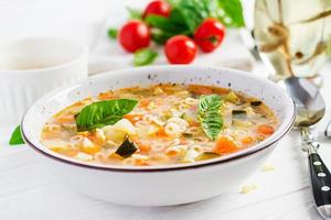 Minestrone, italian vegetable soup with pasta on white table. Vegan soup. photo