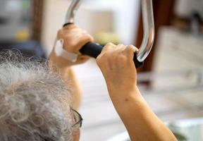 Older handicapped woman using resistance stretch band exercise for patient on a bed at the ward hospital. photo