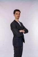 Portrait of young handsome businessman wearing suit standing with crossed arms with isolated on studio white background photo