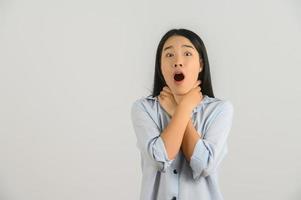 retrato de una joven asiática emocionada con la mano en la camisa azul en el cuello aislada de fondo blanco foto