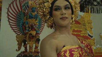 un' bellissimo balinese donna danza nel davanti di un ornato cancello con un' oro corona su sua testa video