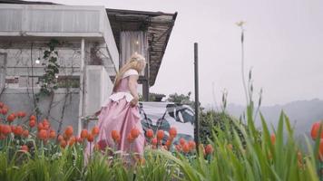 A Princess in a pink dress playing with the tulip flowers in the garden lonely by herself video
