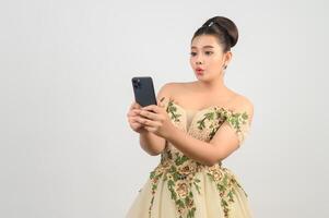 Young asian beautiful bride posting with smartphone in hand photo