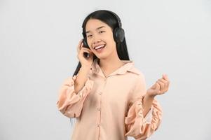 Portrait of Young asian woman with headphone expressing surprise while using mobile phone isolated over white background photo
