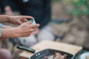 Young women cooking and use smartphone take photo on camping