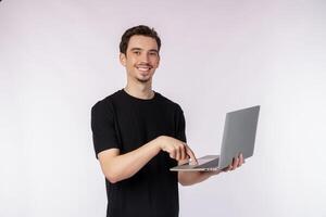 retrato de un joven apuesto hombre sonriente sosteniendo una laptop en las manos, escribiendo y navegando por páginas web aisladas de fondo blanco foto