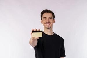 retrato de un joven apuesto sonriente con ropa informal que muestra una tarjeta de crédito aislada sobre fondo blanco foto