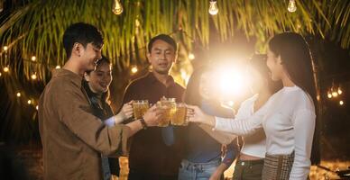 Portrait of Happy Asian friends having dinner party together - Young people toasting beer glasses dinner outdoor  - People, food, drink lifestyle, new year celebration concept. photo