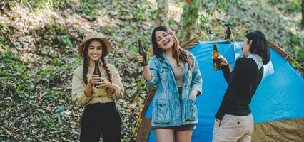 Young woman cheer and drink beverage front of camping tent photo