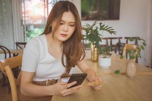 Young woman using credit card and mobile phone for online shopping in cafe, coworking space or coffee shop. Technology money wallet, online payment concept, credit card mockup. Safe mobile banking photo