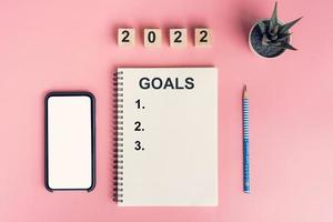 Notebooks with empty goals for 2022 year and phone on color background photo