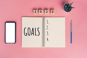 Notebooks with empty goals for 2022 year and phone on color background photo