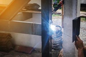 Man welder doing a metal staircase structure in a residential building using a welding machine. photo