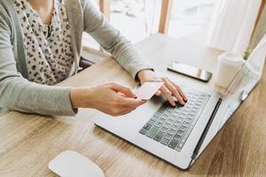 woman using smart phone and credit card for shopping online in coffee shop photo