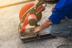 Worker man cutting steel with a circular steel cutter. photo