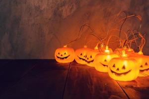 fondo de halloween, luces de cadena de calabaza en la mesa de madera foto