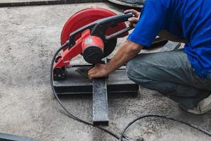 Worker man cutting steel with a circular steel cutter. photo