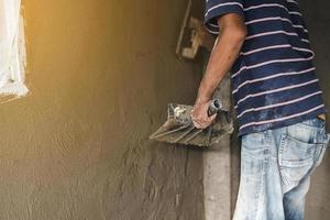 mano de hombre trabajador enyesando una pared con paleta foto