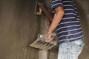 worker man's hand plastering a wall with trowel photo