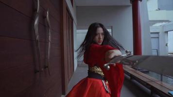 una mujer china agitando una espada plateada mientras usa un vestido chino rojo video