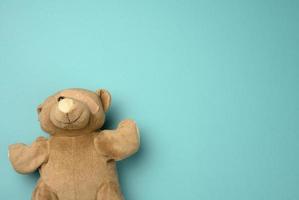 old teddy bear with a band-aid on the eye lies on a blue background photo