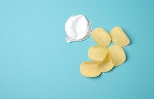 round potato chips and foil lid on blue background, top view photo