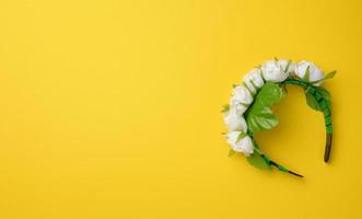 decorative headdress hoop with white roses on a yellow background. Wreath for costume photo