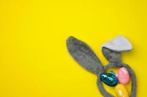 decorative easter eggs and long ears plush bunny toy on a yellow background photo