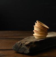 pila de tartaletas en blanco redondas horneadas en tablero de madera, fondo negro foto