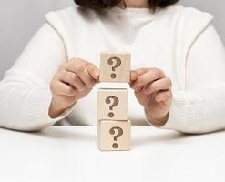 female hand holding a wooden cube with a question mark, concept of answers and questions, suspense and solution methods, close up photo