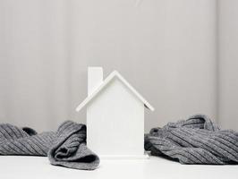 white wooden miniature house wrapped in a gray knitted scarf. Building insulation concept, loans for repairs photo
