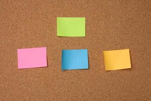 multicolored square sticks are glued to the brown cork texture photo