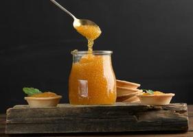 salted pike caviar in a glass jar on a wooden board, close up photo